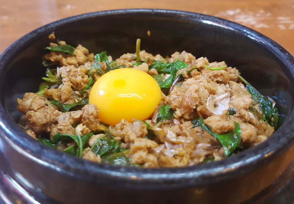 egg on top of  ground pork in black bowl - best thai food in thailand