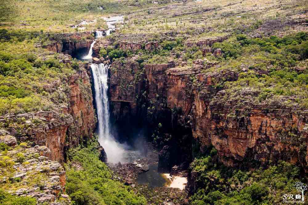 aerial view of the park showing a falls in the middle of a rock mountain with bushy green plants on top