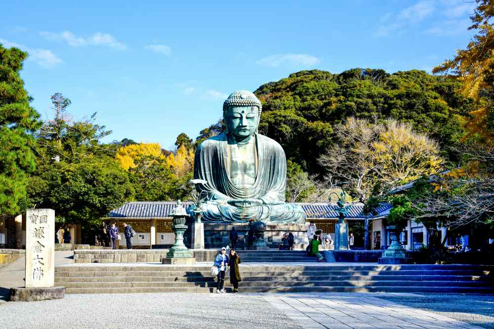 people in front of a giant buddha statue surrounded by trees - best things to do in Tokyo