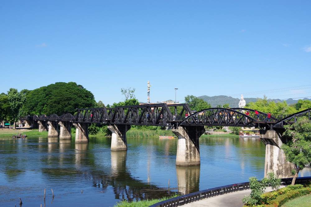 people walking and passing by the black bridge - best places to visit in thailand