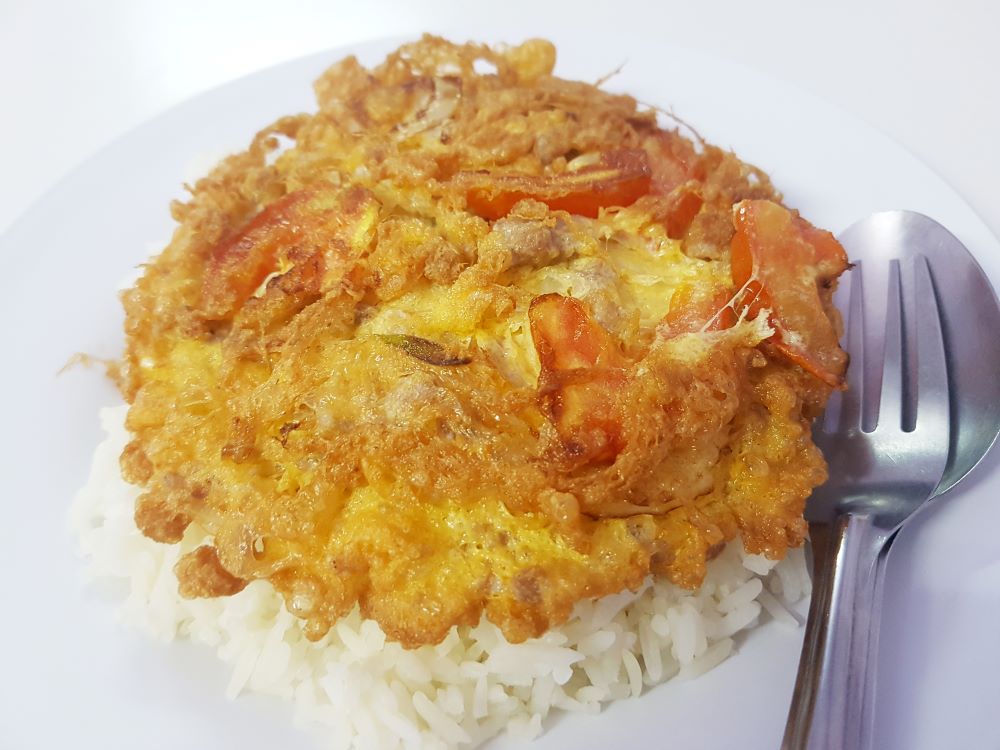 omelette on top of white rice with spoon and fork on the side