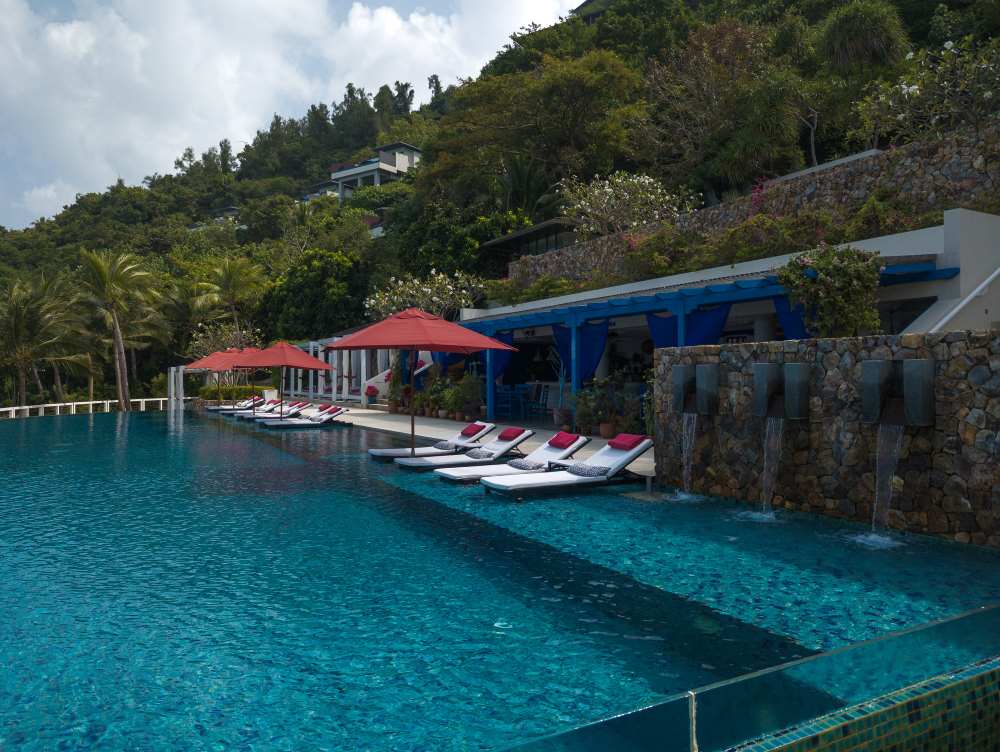 beautiful pool with beach bed on the side and surrounded by green trees - Koh Samui vs Phuket