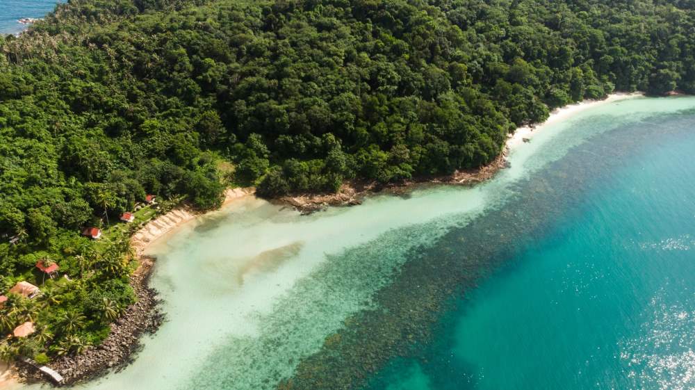 aerial view of a green beach surrounded by green trees- best places to visit in thailand