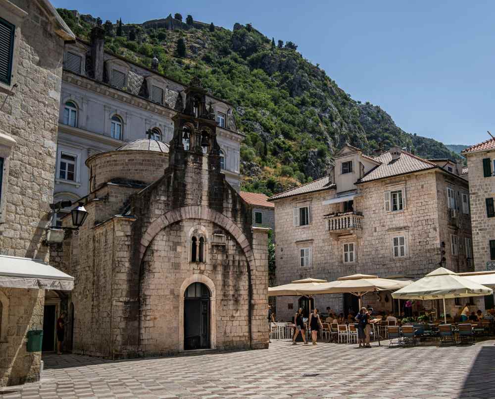 people walking in the street with cafe and old brick building around