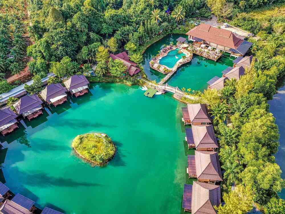 green pool surrounded by cottages and green trees