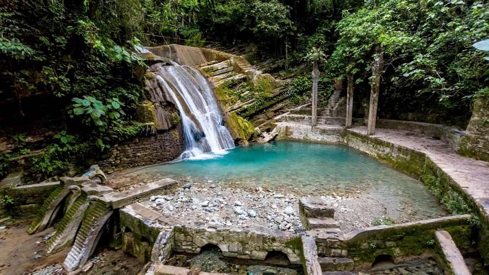 waterfalls surrounded by green trees and old structure made of rock- 25 Best Places to Visit in Mexico