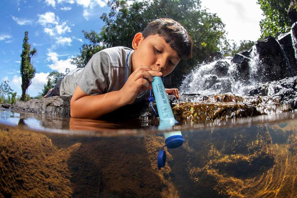 boy drinking water in a stream water using personal water filter