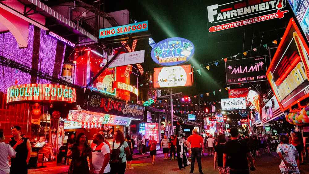 people walking around a busy street full of clubs and establishment during night time