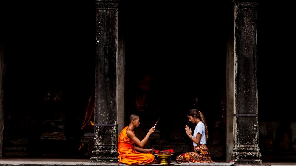 monk and a woman facing each other and meditating