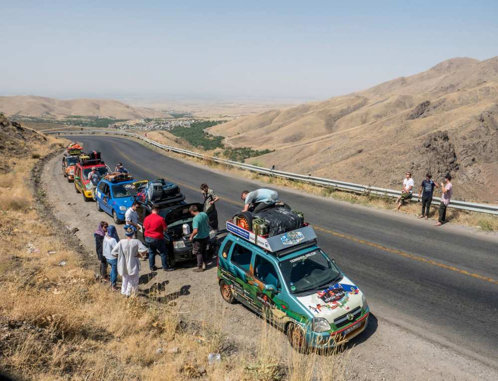 people checking out their cars on side of the road