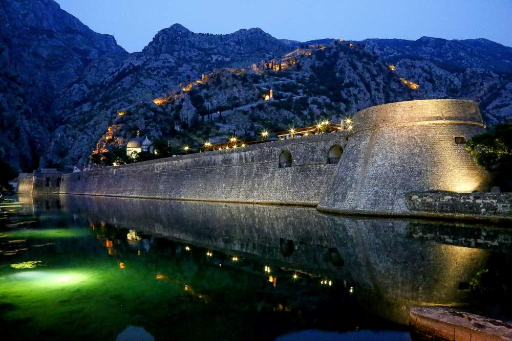castle near the body of water with mountain background