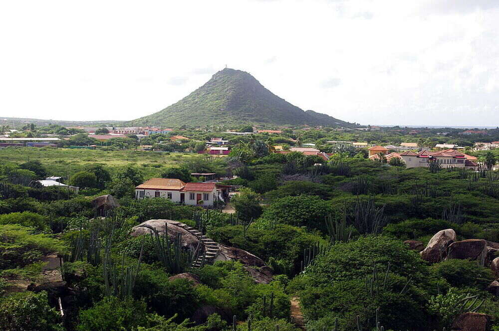Mount Hooiberg with houses in the buttom and green trees around