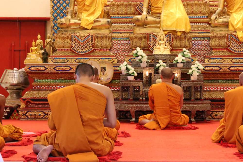 men wearing orange on their knees in front of buddha