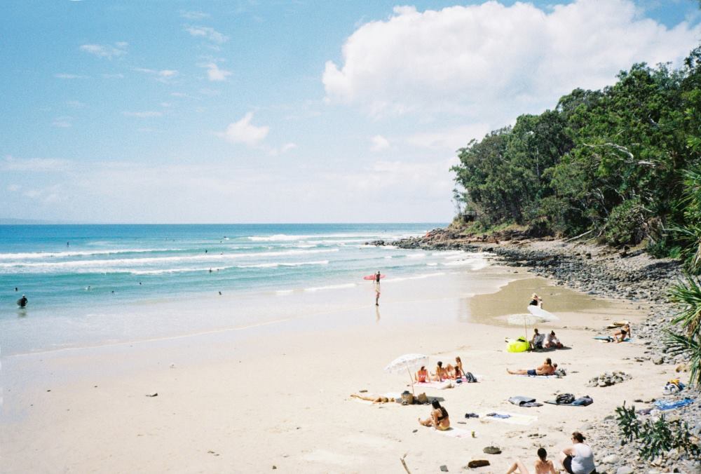 people laying sunbathing on the sand near the beach