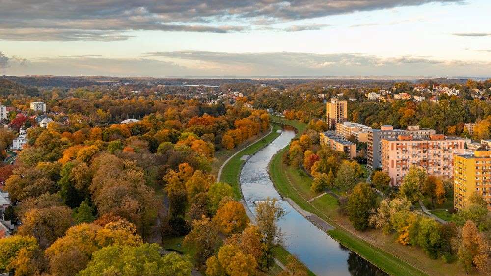 aerial view of a river in between a community with buildings and green trees - czech republic digital nomad visa