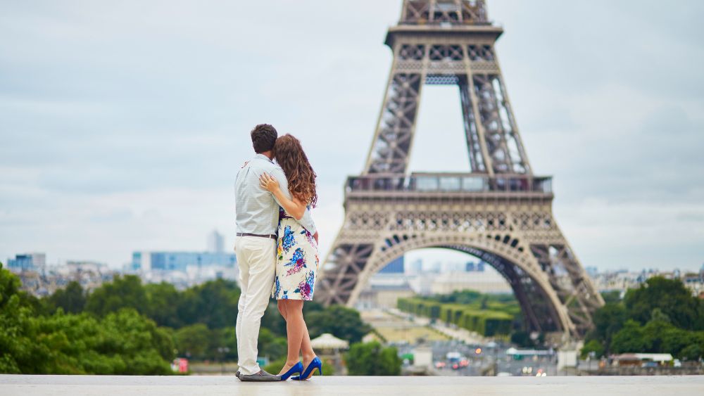 couple hugging in front of the Eiffel Tower in Paris