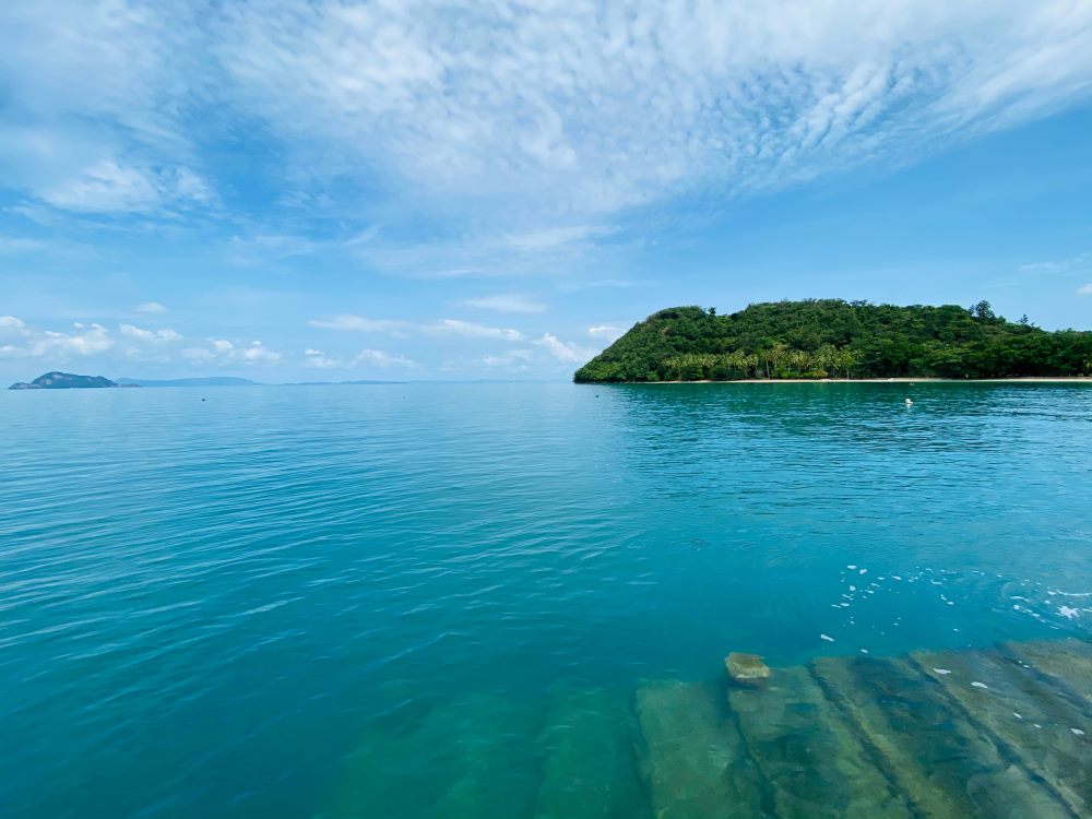 blue clear ocean  with green trees on the background