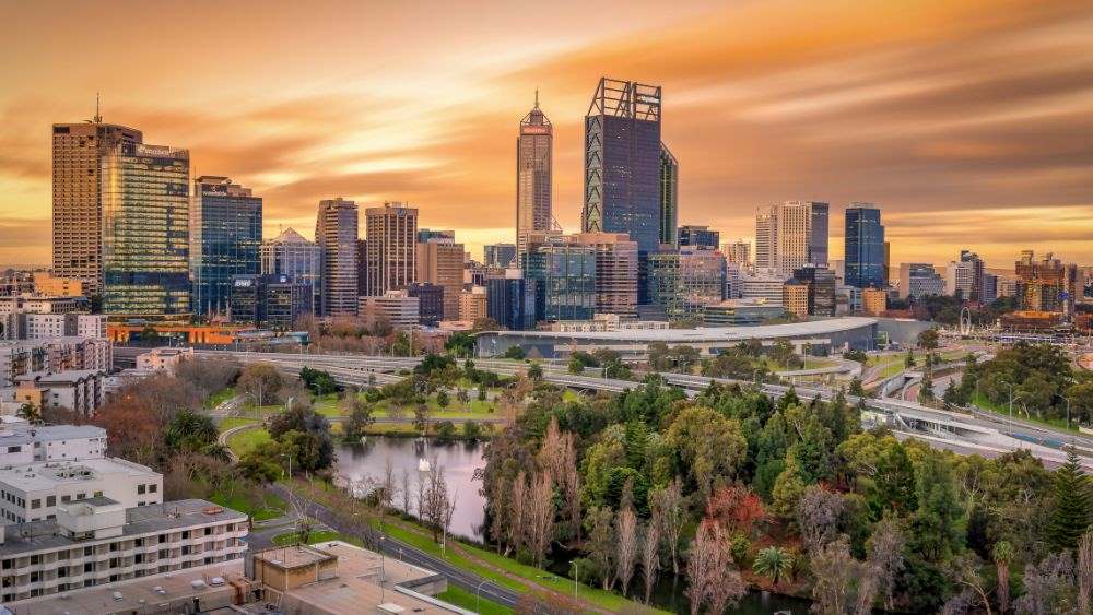 aerial view of the city with high rise buildings and city roads in front is a park with green trees - Best Places to Visit in Australia