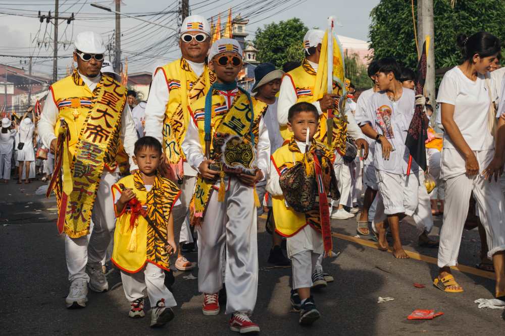 people walking in the street with overall white shirt and pajamas and some has yellow sash and flags