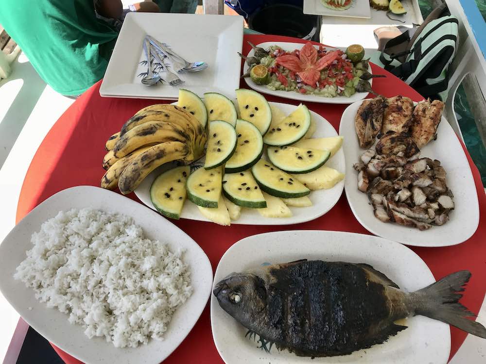 steam fish, rice, pork and fruits in the table