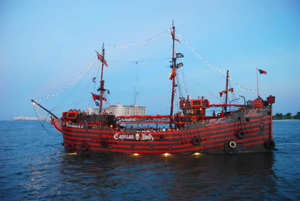 red pirate like ship with people inside sailing in the middle of the ocean- Best Things to Do in Cancun Mexico