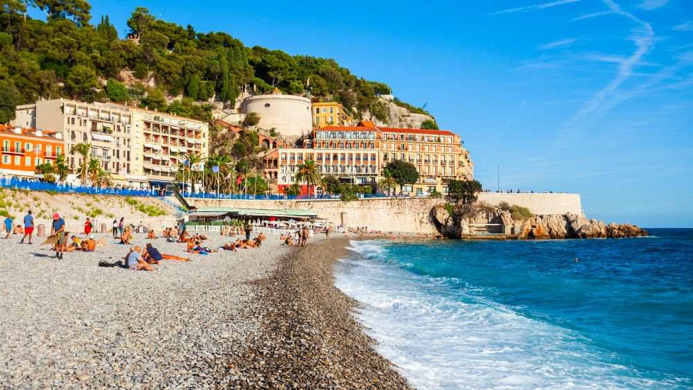 people sitting in the sand in front of  the beach - Things to do in Nice, France