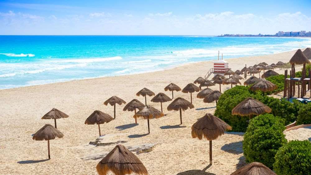 white sand beach surrounded by nip hut in umbrella style