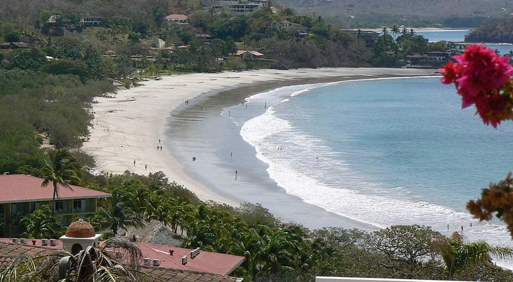 top view of the Playa Flamingo Beach, Guanacaste with people by the bay trees all over with some resorts nearby