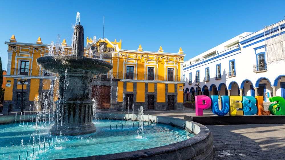 fountain in front of a yellow building beside the "PUEBLA" signage
