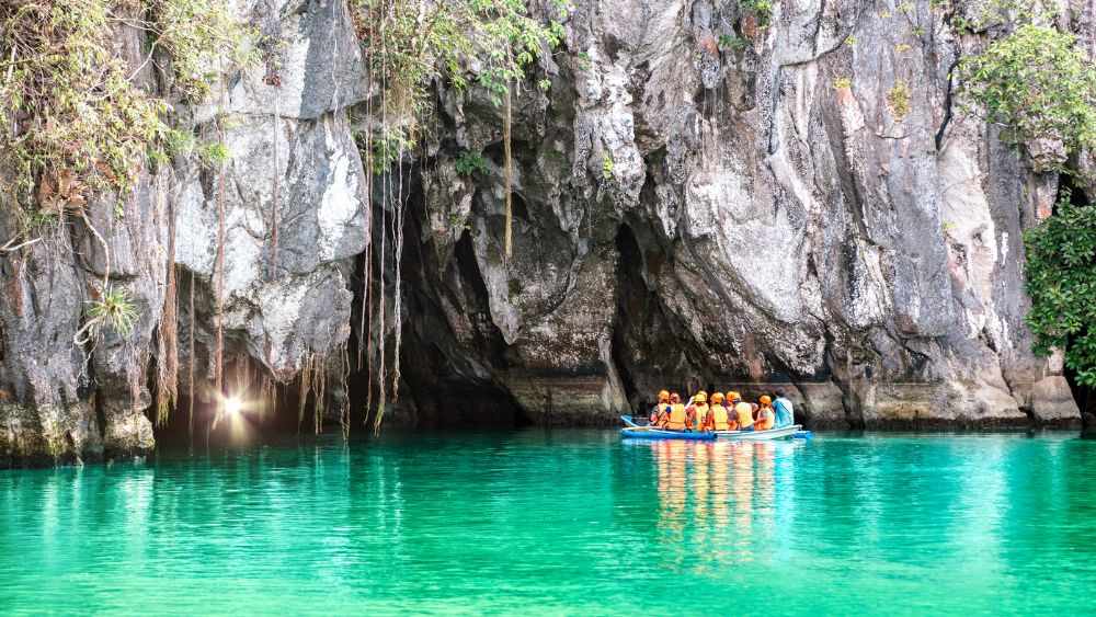 people sitting in a boat going inside the cave