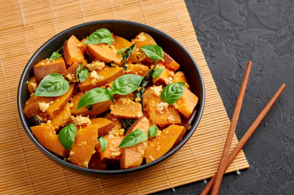 cooked pumpkin in stir fry out in black bowl with wooden chopstick on the side