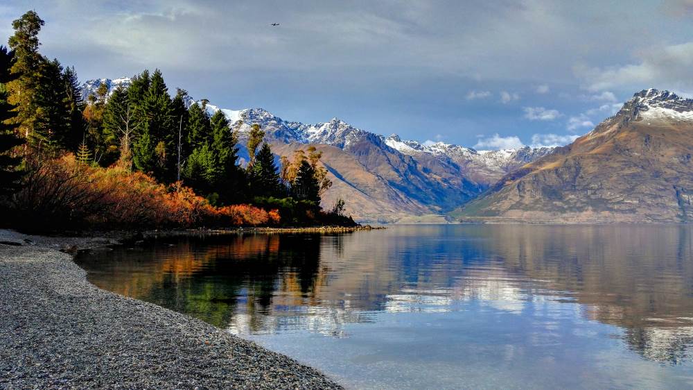 body of water surrounded by trees and mountains