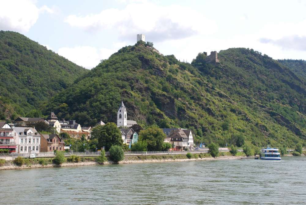 small town near lushy green mountain in front of the body of water - medieval villages in europe