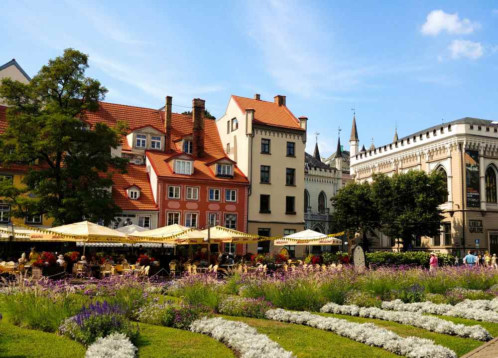 buildings with umbrella and table in front is a green field with flowers- latvia digital nomad visa