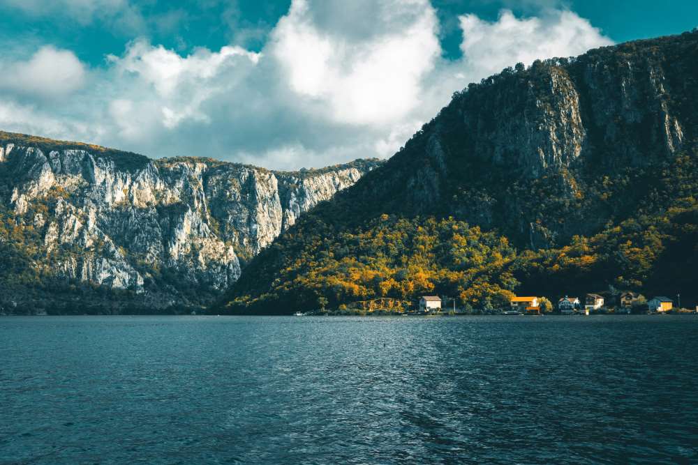 mountains surrounded by green trees in front is a body of water