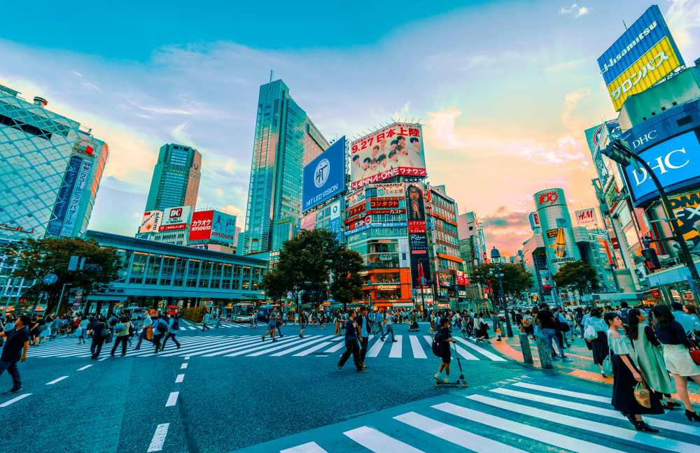people walking in a busy street full of high rise buildings - best things to do in Tokyo