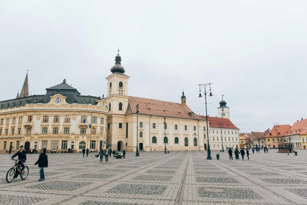 people walking and sitting in an open space in front of the concrete buildings- romania digital nomad visa