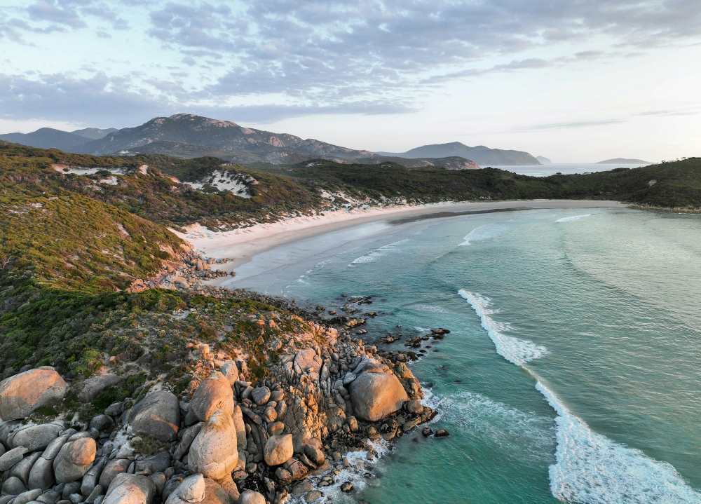 aerial view of a lushy rocky hill in front of the ocean - Best Beaches in Australia