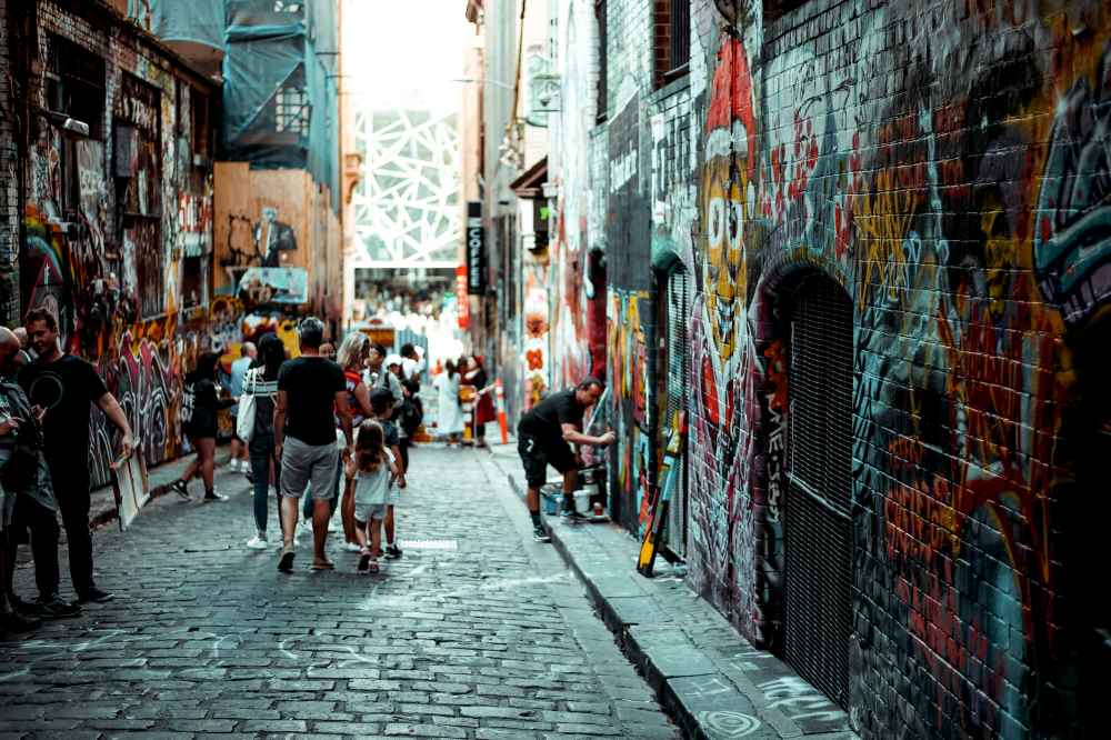 people walking in a street alley full of wall arts