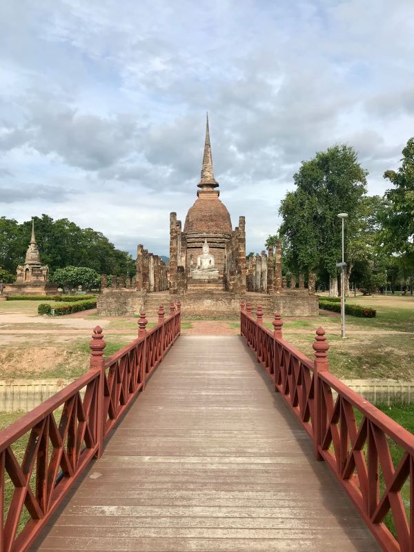 red bridge going to the brown concrete structure with statue in the middle- best places to visit in thailand
