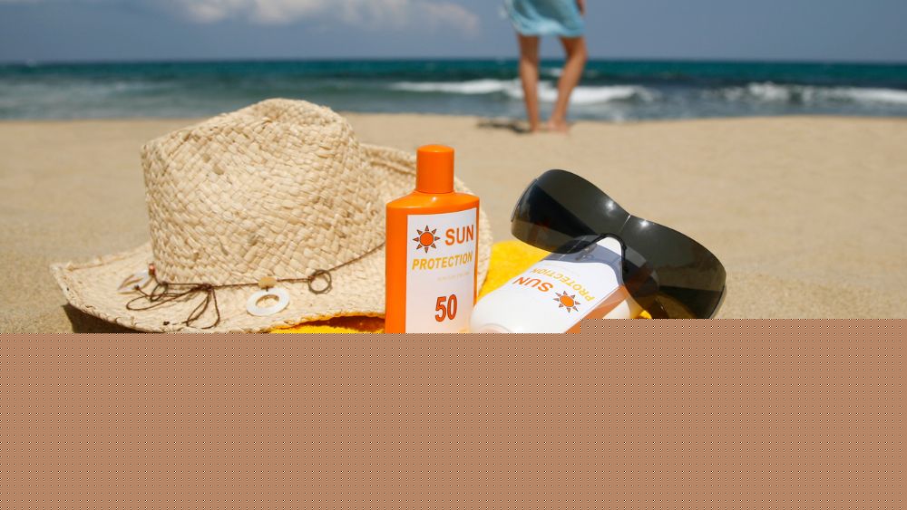 hat, sunglass, sunscreen and yellow towel at the sand near the beach - is australia safe?