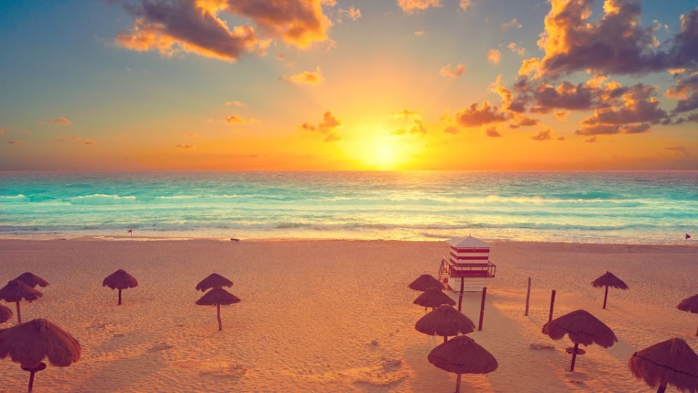 sunset in front of the beach with umbrella like nipa hut- Best Things to Do in Cancun Mexico