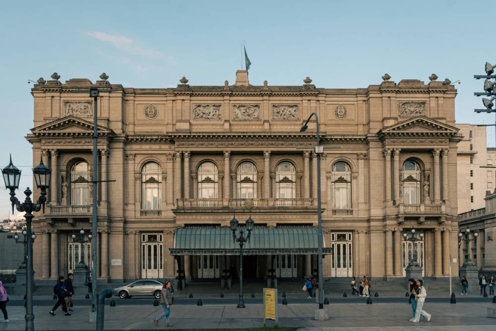 large old structure building beside the road with people passing by