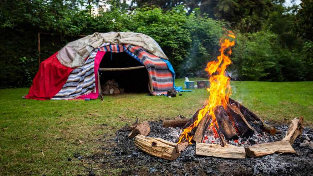 cloth made dome-shaped sweat lodge in the middle of the forest with bonefire