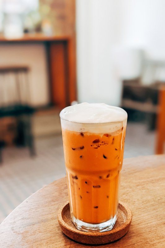 glass of orange tea on top of a wooden table- facts about thailand