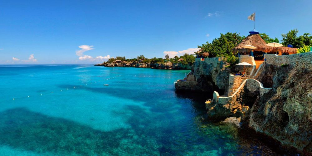 nipa hut structure near the cliff beside turquoise Caribbean waters