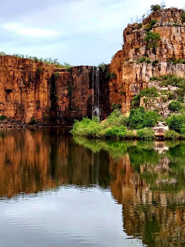 waterfalls in the middle of the stone mountain with body of water down - Best Places to Visit in Australia 