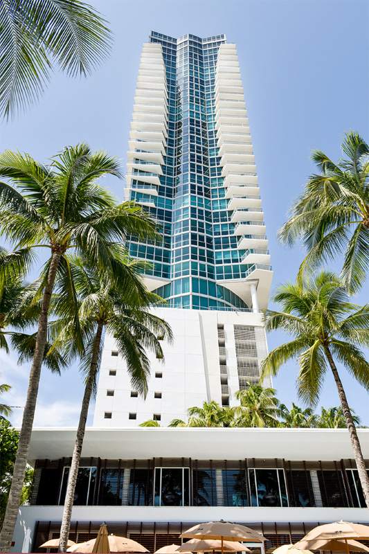 vertical high rise white hotel with palm trees around