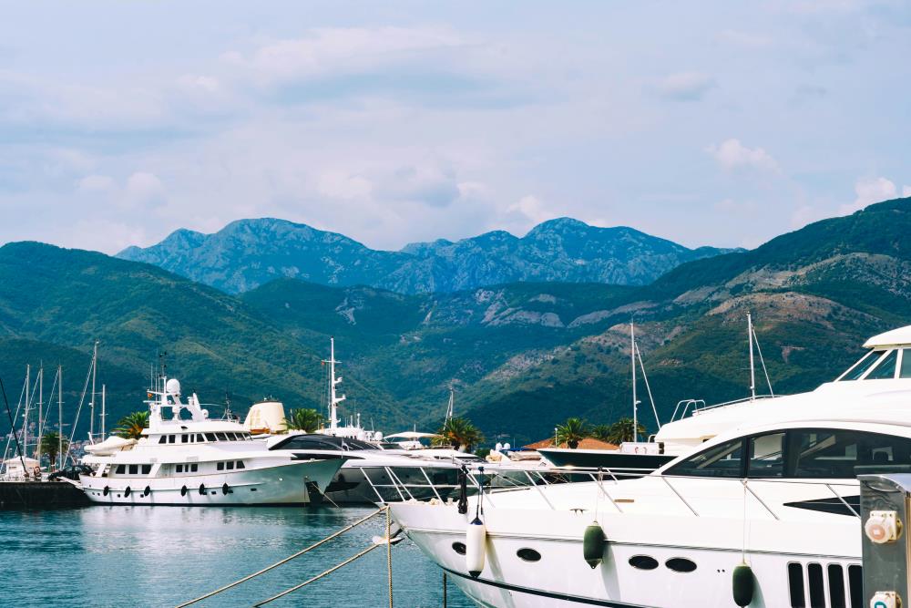 white yatch on the body of water with green hills on the background- montenegro digital nomad visa