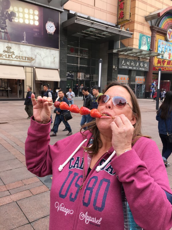 image of a woman in pink jacket eating toffee strawberries - beijing